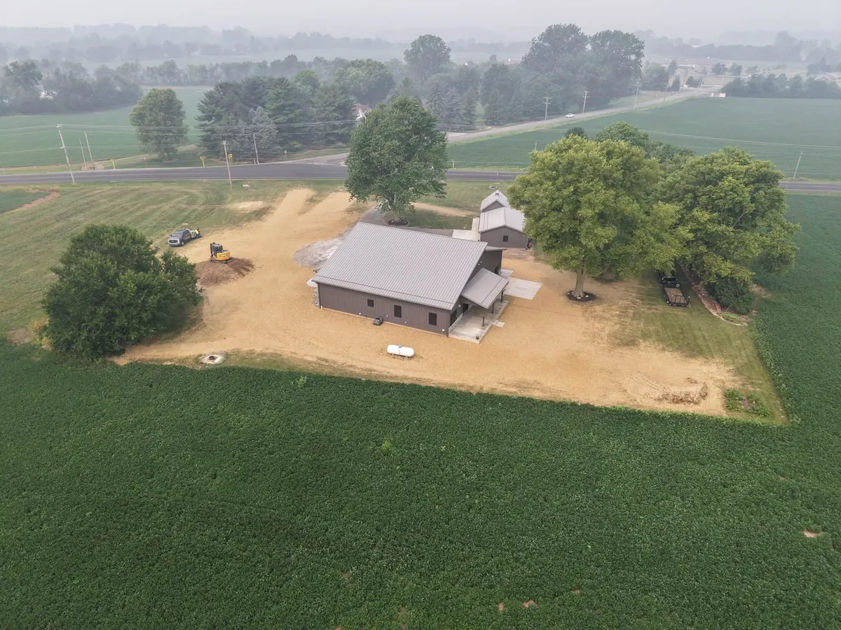 Aerial view of a new home on acreage with graded ground surrounded by farm fields