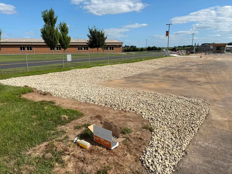 Drainage stone installed along paving in front of a school building