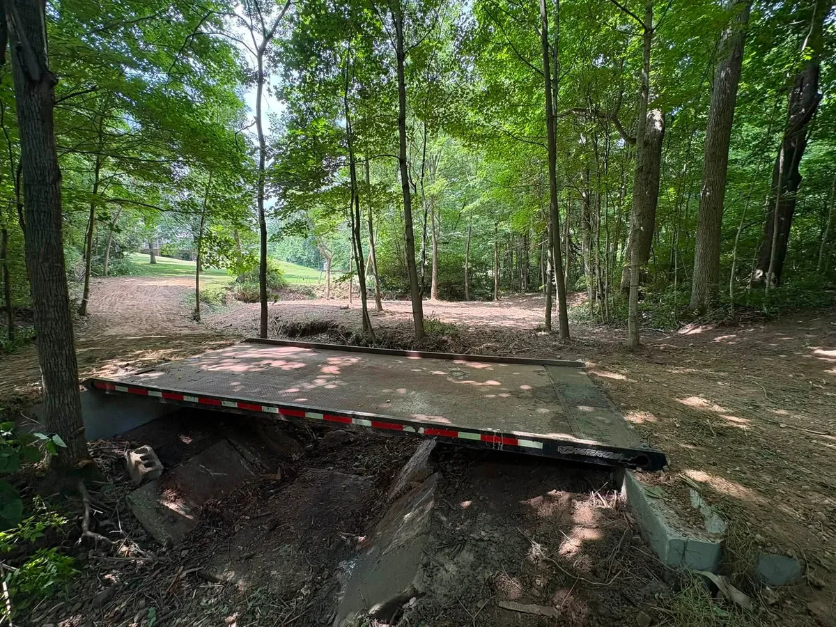 New flat crossing over culvert pipe in a wooded creek bed