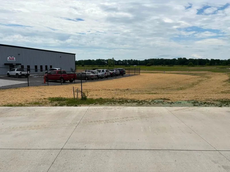 Seeded and strawed site beside a new concrete apron and industrial building