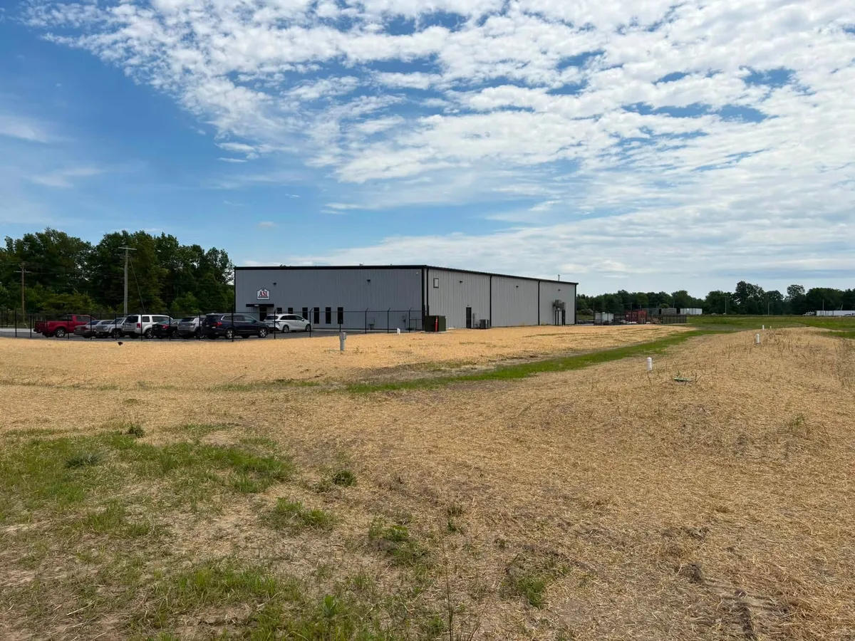 Graded and strawed ground in front of a large metal industrial building