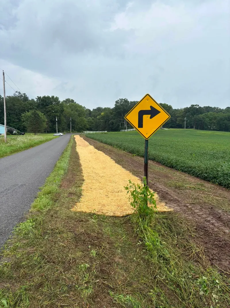 Restored berm seeded and strawed beside a curve warning sign