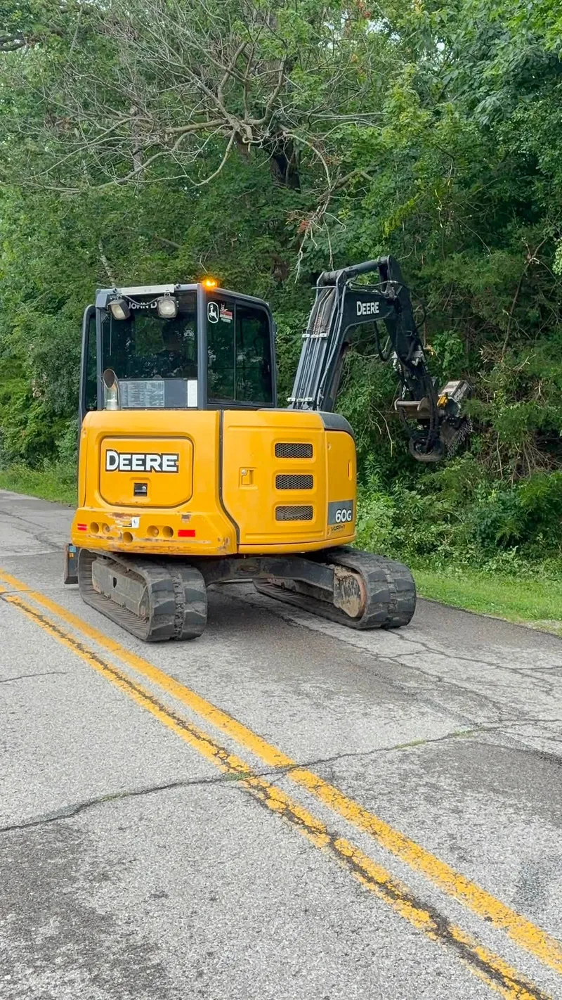 Excavator with a mulching head working along a township road